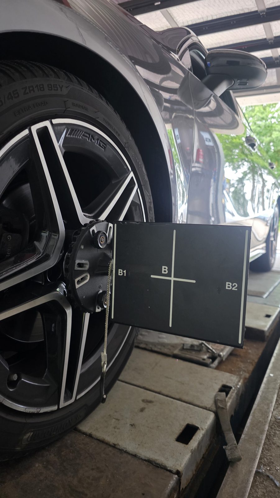 Fahrzeugrad mit montiertem Messkopf zur Achsvermessung auf dem Vermessungsstand einer Kfz-Werkstatt