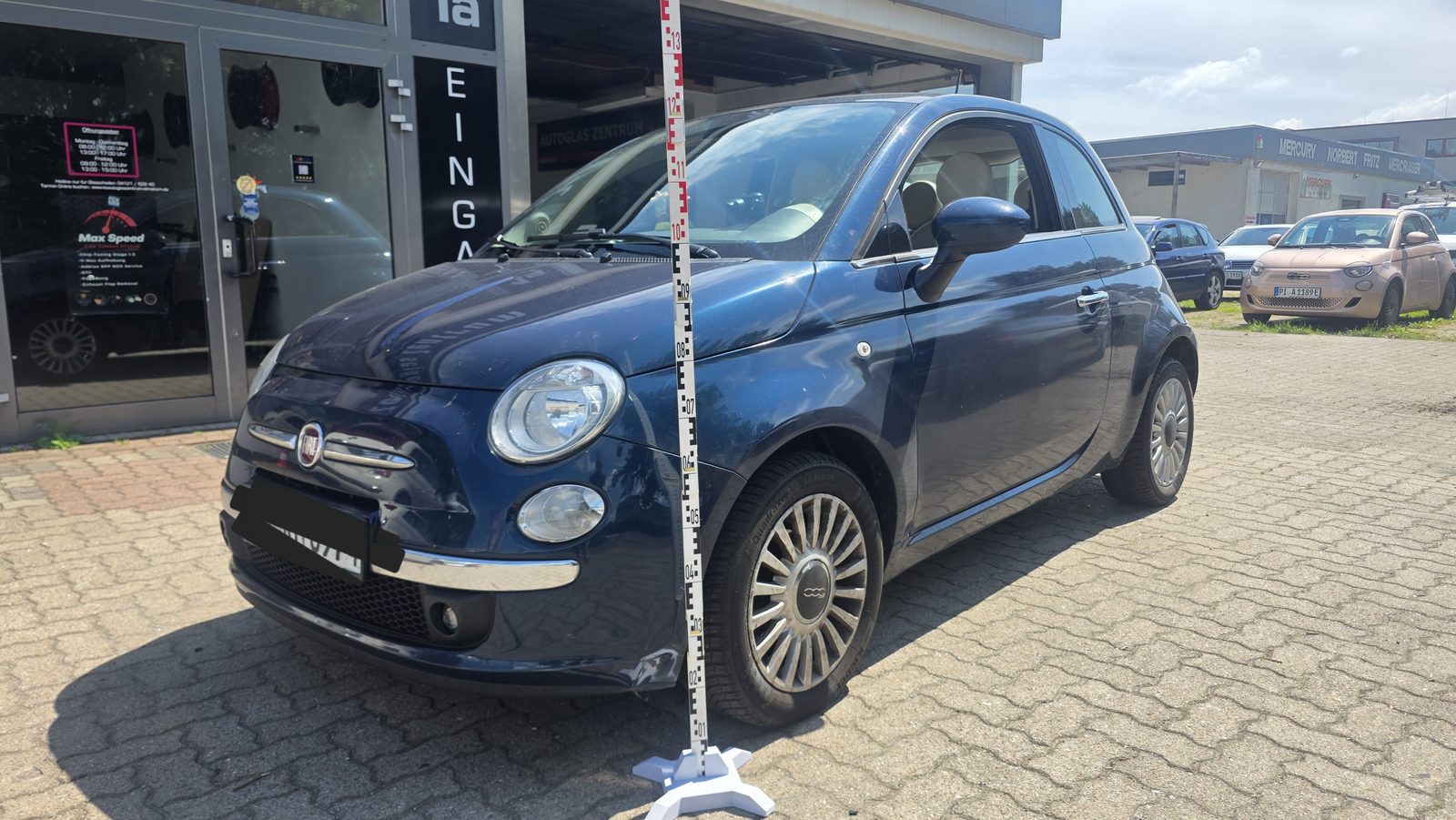 Dunkelblauer Fiat 500 wird mit einer Fotomessleiste für ein unabhängiges Kfz-Gutachten vermessen und dokumentiert